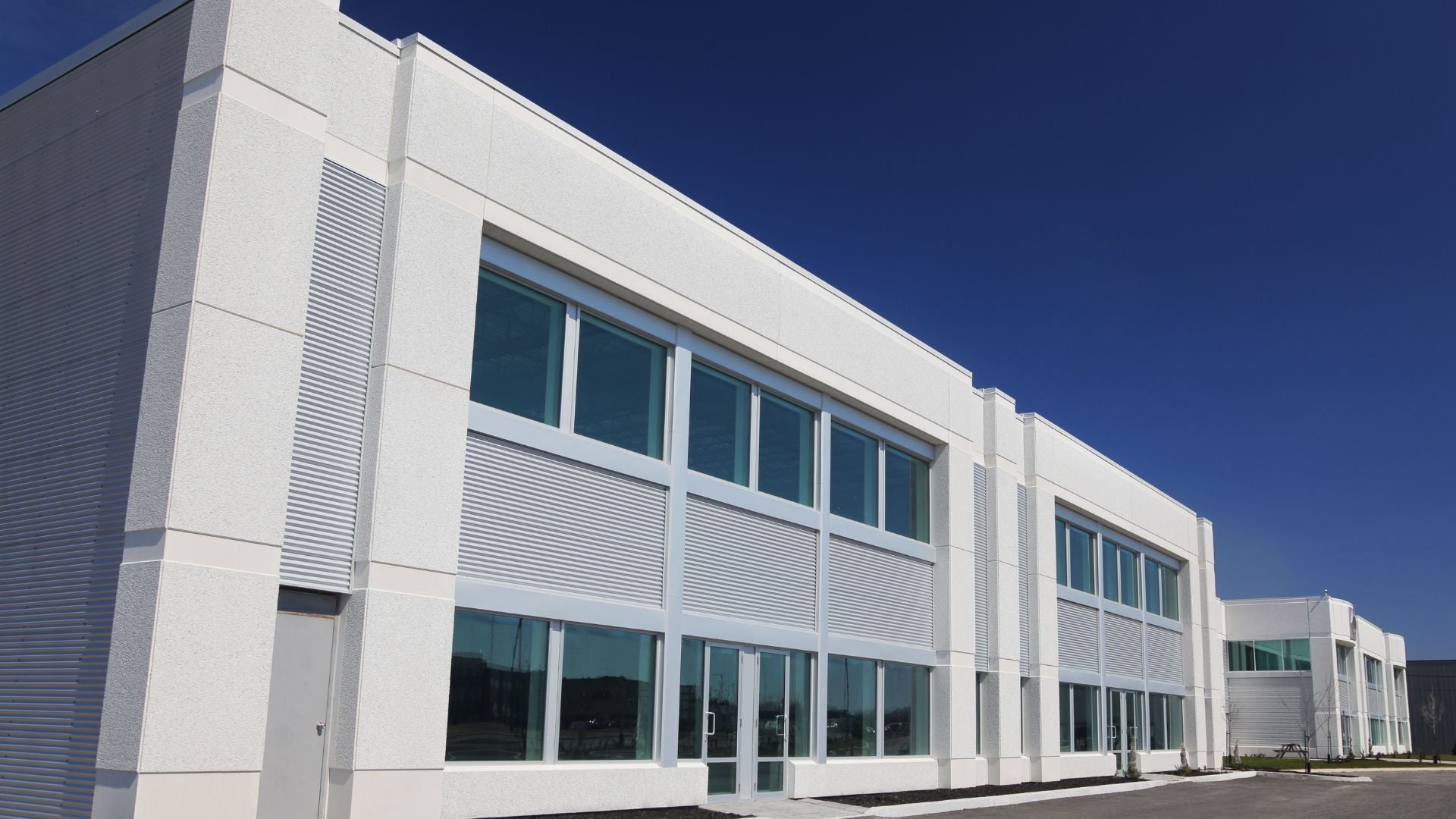 Modern commercial building with white exterior paint and large windows under a clear blue sky — Diamond Brite industrial coatings.