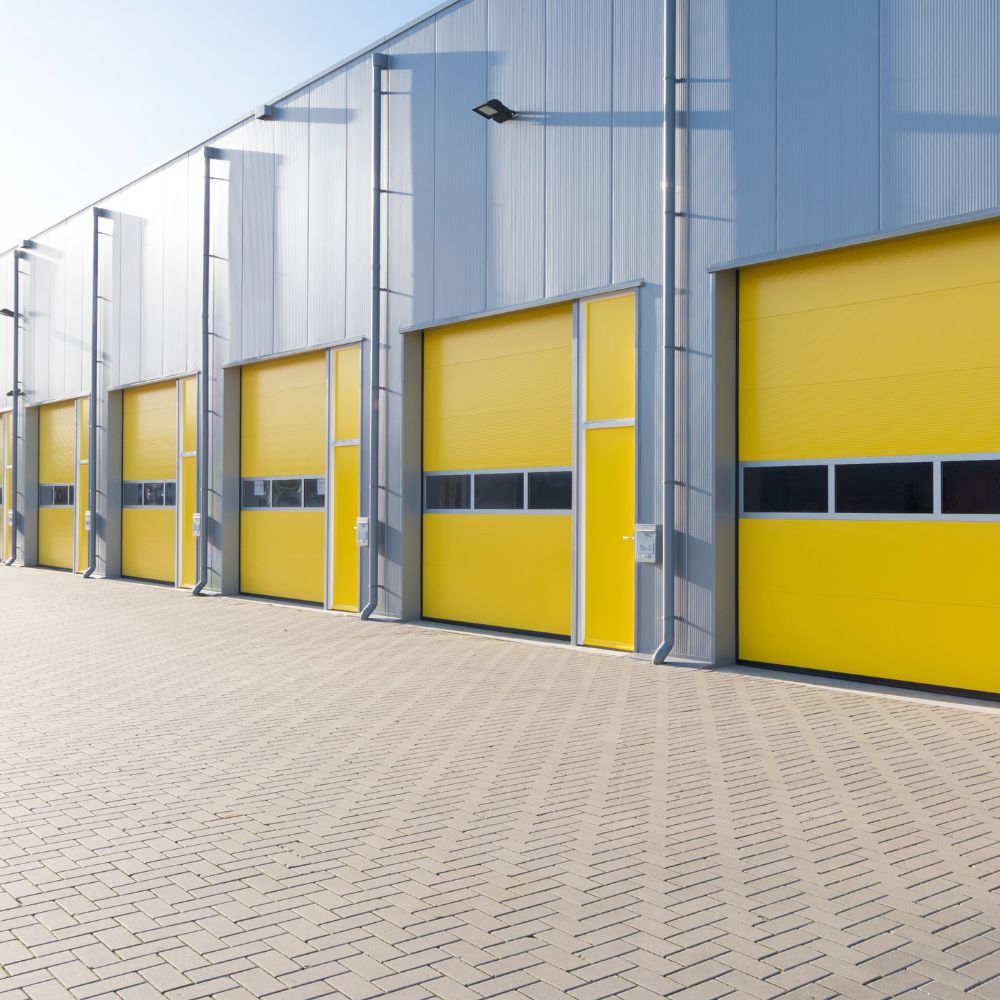 Commercial warehouse exterior with bright yellow roll-up doors—Diamond Brite industrial coatings.