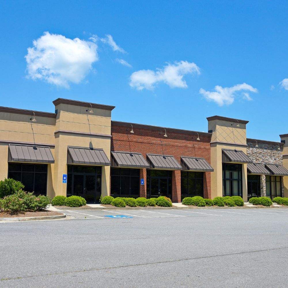Retail plaza storefronts painted with durable exterior masonry paint under a blue sky.